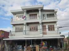 Лаосский жилой дом с флагом страны, на первом этаже - магазин