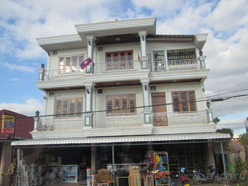 Лаосский жилой дом с флагом страны, на первом этаже - магазин