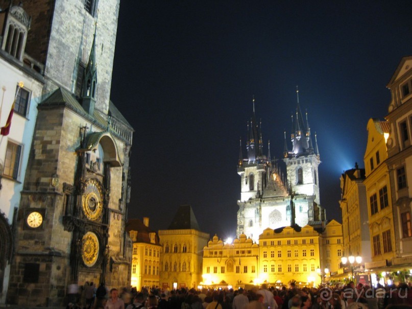 Дальше двигаемся на Староместскую площадь. Здесь часто проходят какие-то концерты, массовые гуляния и праздники. Она особенно красива в вечернем освещении. Слева вы видите астрономические часы, которые являются местом паломничества всех туристов. Каждый час, когда бьют часы, происходит небольшое представление в традициях средневекового кукольного театра.