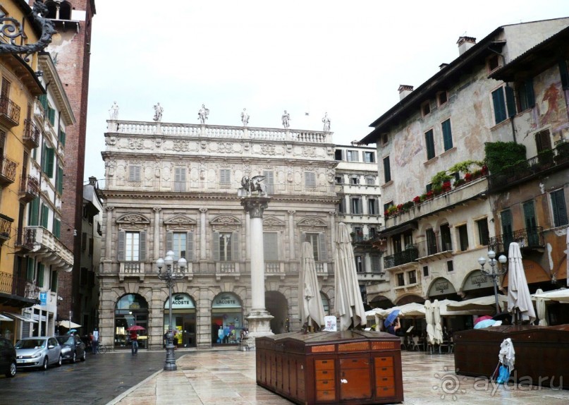 Вскоре мы выходим на центральную площадь города – площадь Трав, Пьяцца делле Эрбе. Глубоко под площадью – руины римского ипподрома и форума, а на ее территории сегодня – городской рынок. А ведь именно здесь когда-то выступали перед подданными герцоги делла Скала (те самые Скалиждеро), здесь Тибальд убил в поединке несчастного Меркуцио, здесь были произнесены знаменитые слова: «Нет повести печальнее на свете…». На заднем плане здание Палаццо Маффеи, перед ним стоит колонна со львом Св.Марка.