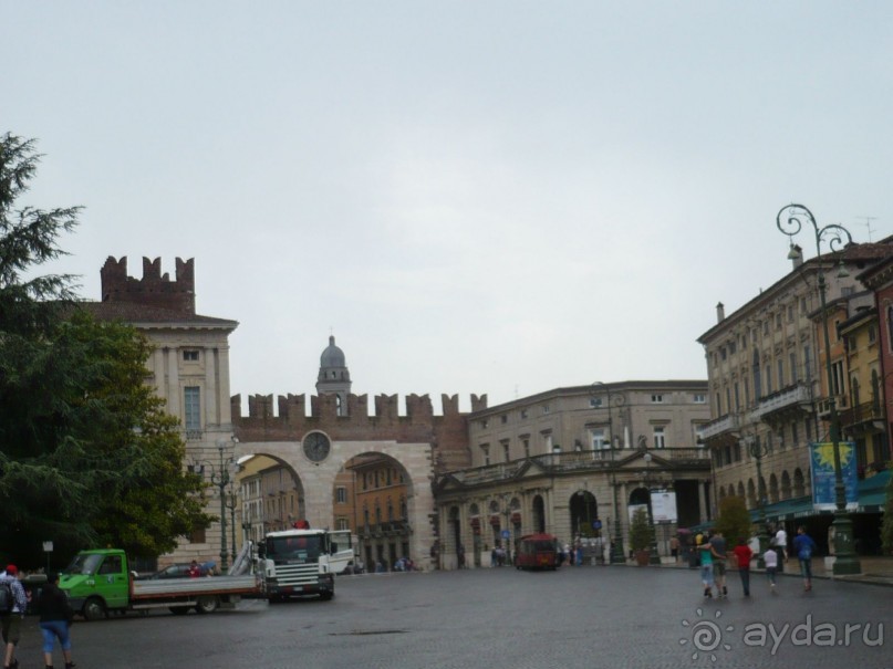 Арена ди Верона стоит на самой просторной площади Вероны – Пьяцца Бра. Это излюбленный променад горожан и туристов с самыми дорогими ресторанами и кафе. Вот за этими воротами с зубцами, как на Кремлевских стенах, нас ждал наш микроавтобус, на котором мы продолжили наше путешествие по Италии. 

Следующим и конечным пунктом наших передвижений должна стать Венеция.Но про Венецию в следующий раз.