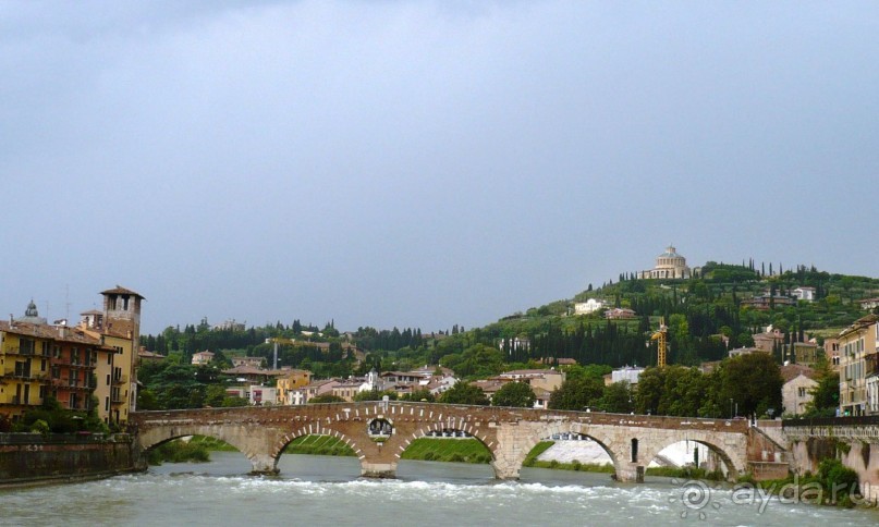 Еще один памятник истории, сохранившийся с античных времён – мост Понте Пьетра (Каменный мост). Этот мост перекинут через реку в месте её самого сильного течения. Он давно стал одним из монументальных символов города, который систематически репродуцируется на многочисленных картинах художников, начиная с XV века и кончая нашими днями. Любопытно, что древнеримскими каменными остались только два пролета. Это белая часть моста. Остальные три пролета построены в XVI веке из кирпича, в некоторых местах перемежающегося с каменными плитами. Именно эта «мозаичность» моста стала основной чертой его очарования.  Опять же любопытный факт того, как горожане трепетно и бережно относятся к своему наследию. Немецкие войска, отступавшие из Вероны в конце Второй Мировой войны, взорвали все городские мосты, не пощадив и античный каменный. Представители Комитета охраны, предвидев такой акт вандализма, тщательно обмерили, подробно сфотографировали, обрисовали все детали и технические особенности моста. Сразу после окончания войны все фрагменты рухнувшего моста были из воды подняты и бережно соединены вновь с воссозданием недостающих частей. Реставрационные работы были выполнены настолько тщательно и превосходно, что, с течением времени, помогли веронцам забыть об этом печальном событии.

