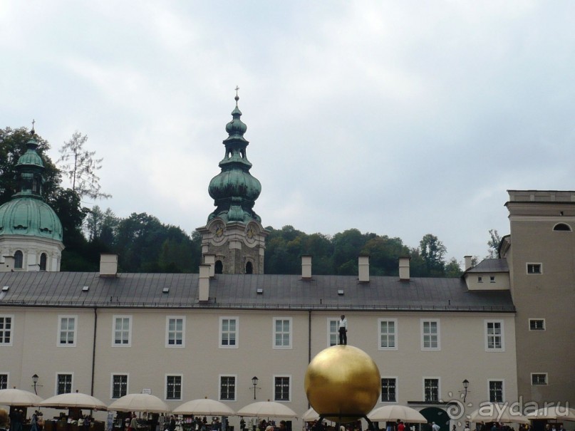 Этот золотой шар я сначала приняла за какой-то цирковой трюк. Думала, что на улице показывается какое-то цирковое представление. Мне казалось, что на шаре стоит живой чернокожий человек. Ничего подобного. Это так называемая современная инсталляция. Поставлена якобы для украшения города. Не знаю, что она там украшает. Среди исторических памятников эта штука вызывает недоумение. Что она собой символизирует, тоже непонятно. Жители Зальцбурга иронично обозвали её между собой «Барак Обама на шаре». Что-то подобное я даже видела возле Лувра в Париже. Так же натыканы современные штуки возле старых скульптур.  Смотрятся крайне нелепо. 

