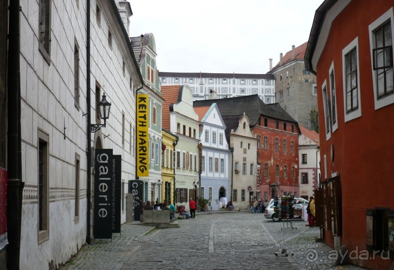 Обратите внимание на окна. Говорят, что когда-то в средние века существовал налог на окна. Деньги в казну платились с каждого окна, выходившего на улицу (на внутренний двор можно было делать сколько хочешь окон). Поэтому хозяева на фасаде прорубали как можно меньше окон. Остальные просто пририсовывали для красоты. Вот, например, на этом фото дом справа. Нам сказали, что здесь одно окно настоящее (там открыта форточка) и три обманных. Сделаны небольшие ниши и в них нарисованы окна.