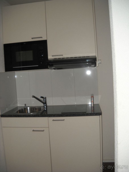    Уголок кухни. Вверху - раковина, плита. Внизу - шкаф с посудой, холодильник. На верхней полке - столовая посуда. Компактно, удобно...