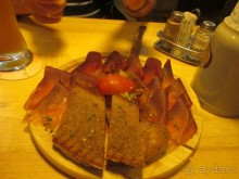 Ветчина из оленины на закуску. К ветчине подают поджаренный черный хлеб с чесноком. 