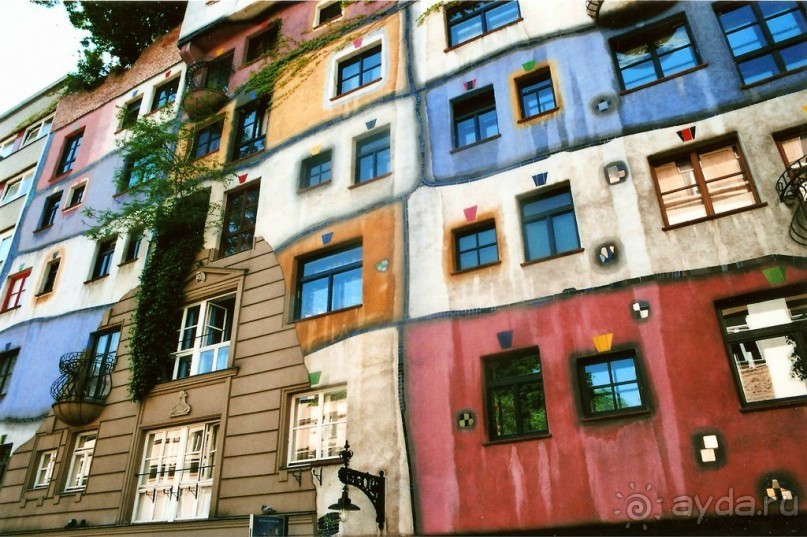 Дом многоцветный – его фасад расчерчен контурами на неровные прямоугольники, окна обведены яркими рамками. Здание необычно по архитектурным элементам: на фасаде разбросаны полукруглые кованые балкончики и ажурные кронштейны для фонарей, вкрапления мозаики и неожиданные рельефы, цветные арочные проёмы и балюстрады с глазурованными колоннами.