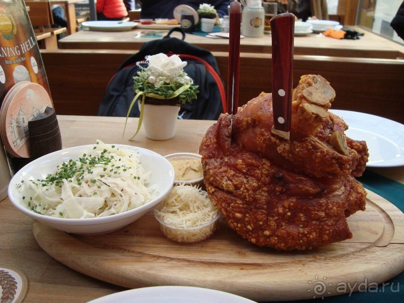 На Ваш выбор предлагается два основных блюда. Прежде всего, это запеченная свиная рулька.  Блюдо по весу может достигать килограмма, поэтому рассчитано на нескольких человек. Подается рулька на деревянном подносе. Кроме мяса, к блюду полагается еще тушеная капуста, молодой картофель, горчица и тертый хрен. 