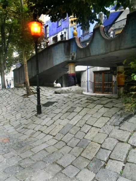 Хундертвассер создавал проекты разноцветных домов с разным уровнем кровли и оконных проёмов, с весёлыми куполами и причудливыми арками, с травой на крышах и деревьями, растущими в нишах жилых квартир.